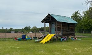 A small building on silts about a meter off the ground.  It's configured for children's play, with slides from the front porch, colorful tires around it, and toys around it.